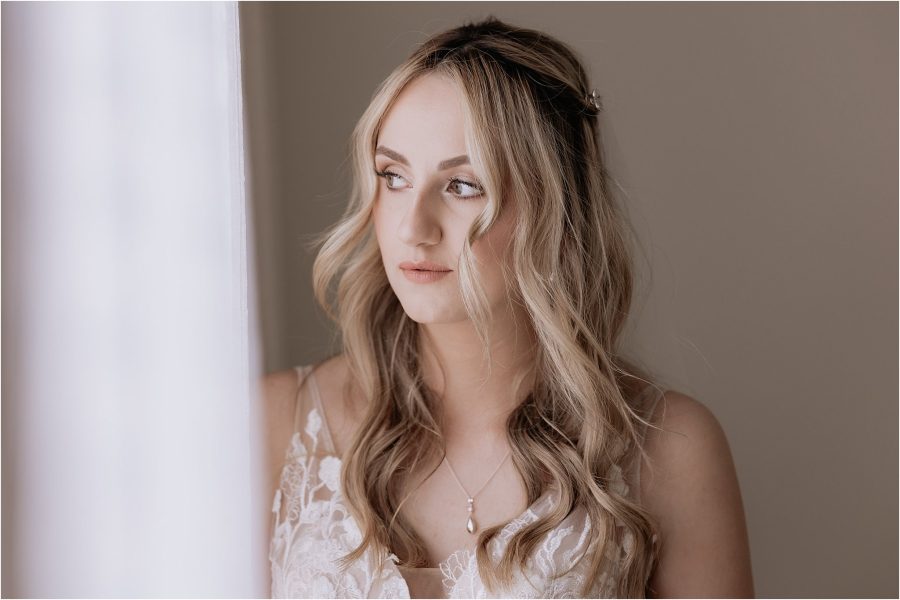 Bride standing beside window before ceremony