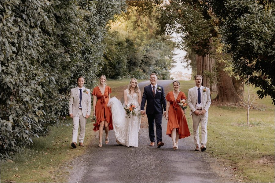 walking bridesmaids and groomsmen in kiwifruit orchard