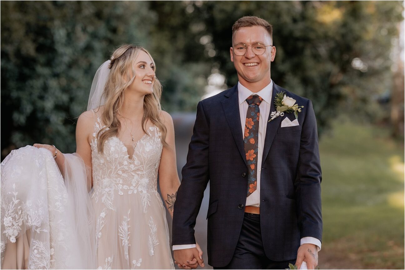 happy groom walking hand in hand with his wife