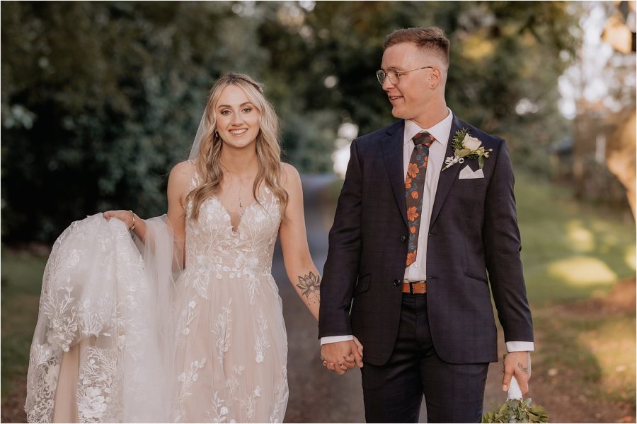 groom and bride walking hand and hand on country drive