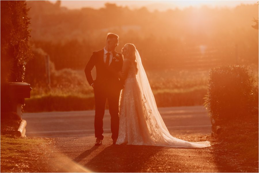 bride leans on groom during golden hour photography time