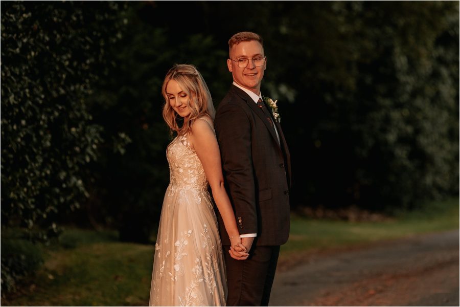 Bride looks down at husbands hand in sunset hour