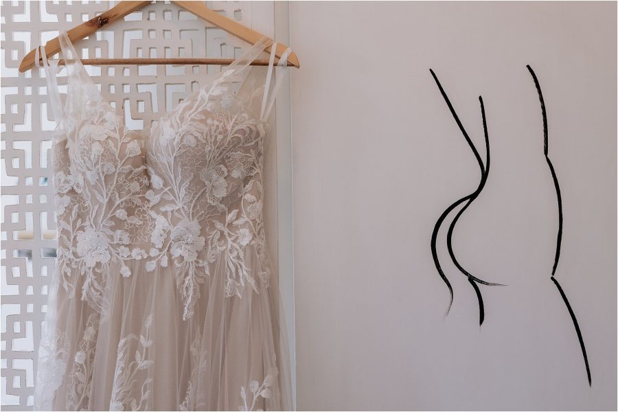 Mad Lane bridal dress hanging beside nude art painting