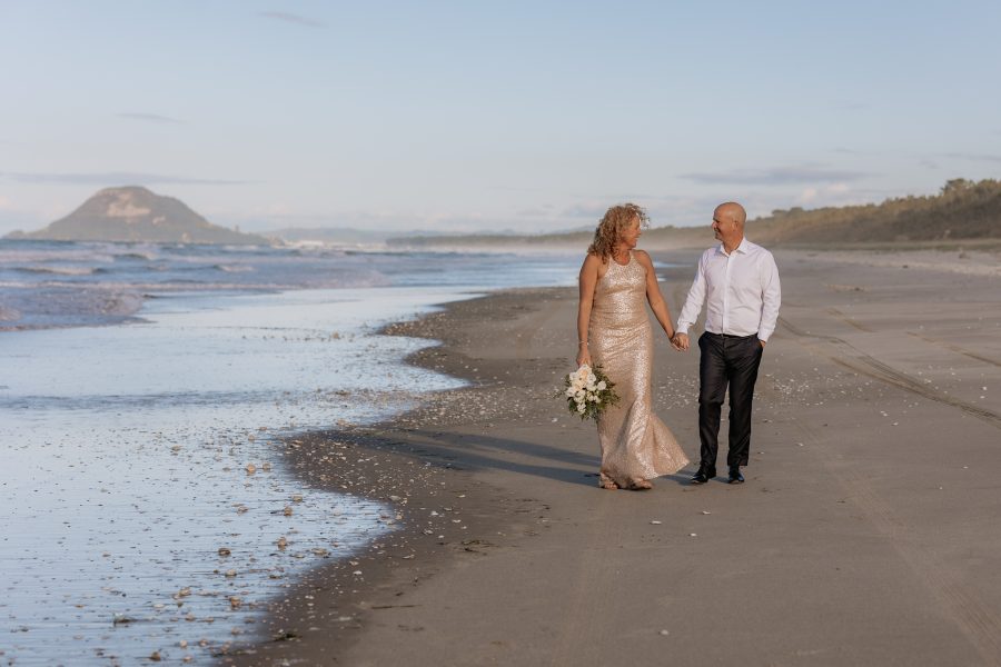 Elopement wedding on Matakana Island walking on beach with Mount Maunganui in back groud