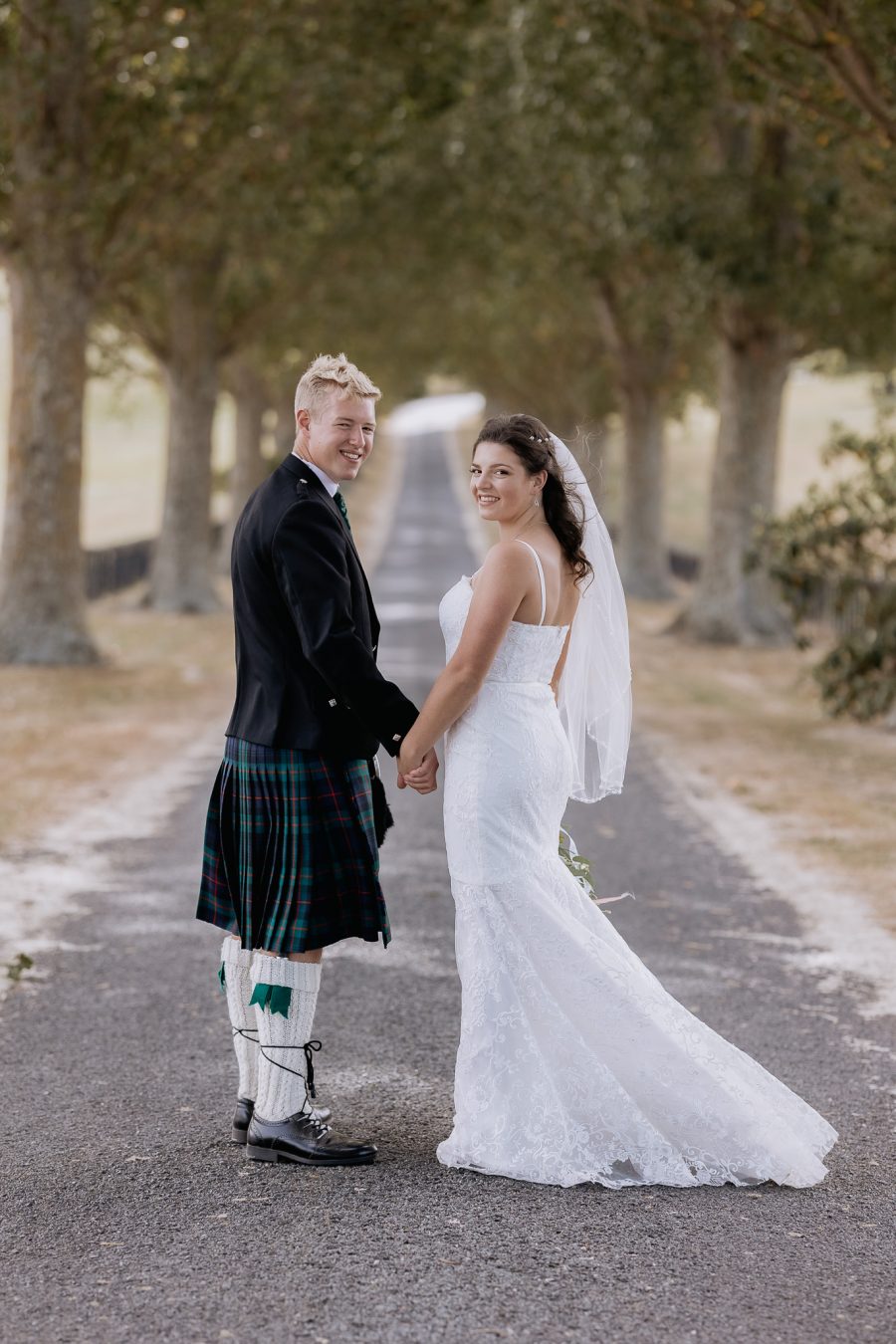 wedding photos on the red barn driveway, couple turning looking at their photographer