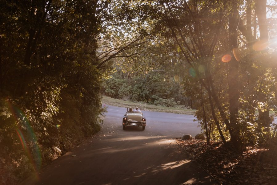 bride and groom driving away in vintage car