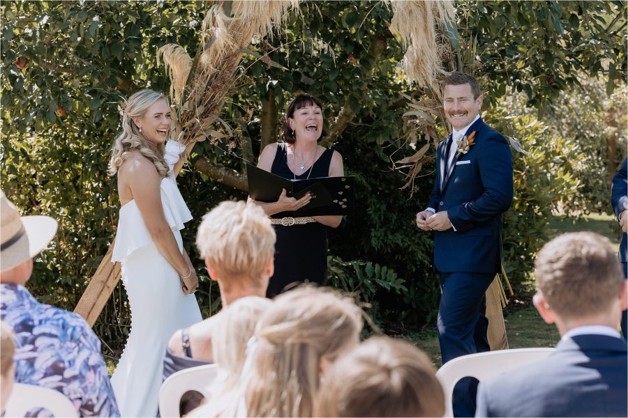 Bride and groom laughing with celebrant