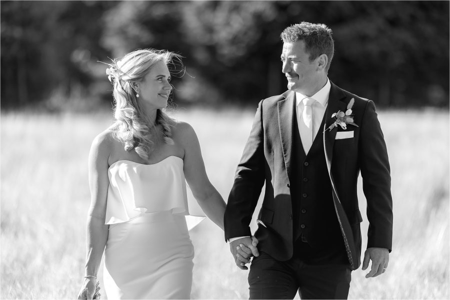 Black and white photo of bride and groom holding hands looking at each other