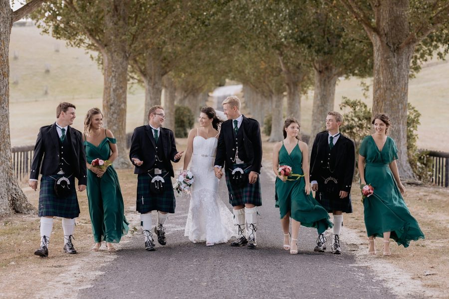 wedding party walking along red barn driveway