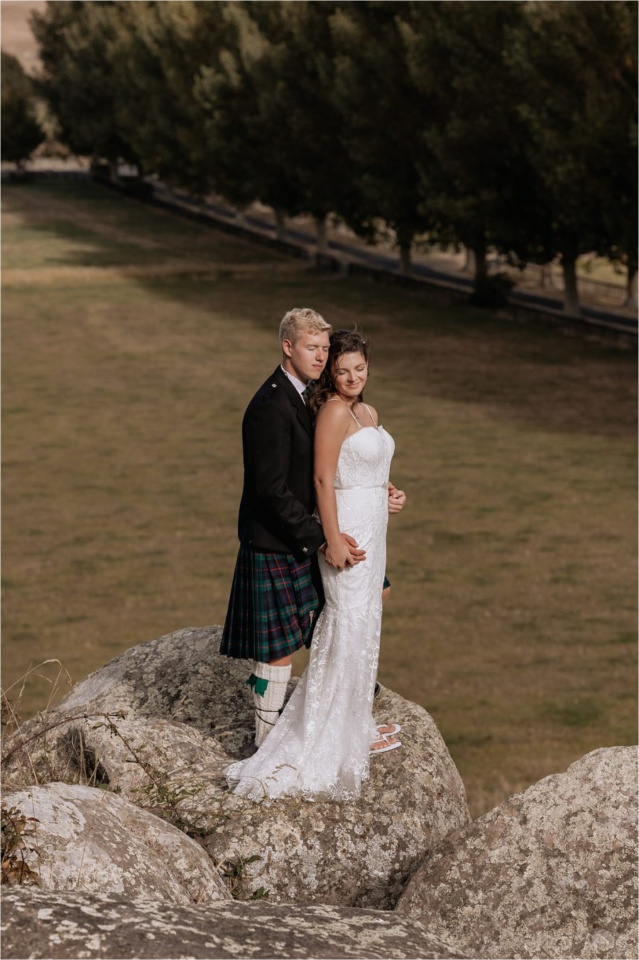 groom and bride cuddling on rock on the farm at red barn