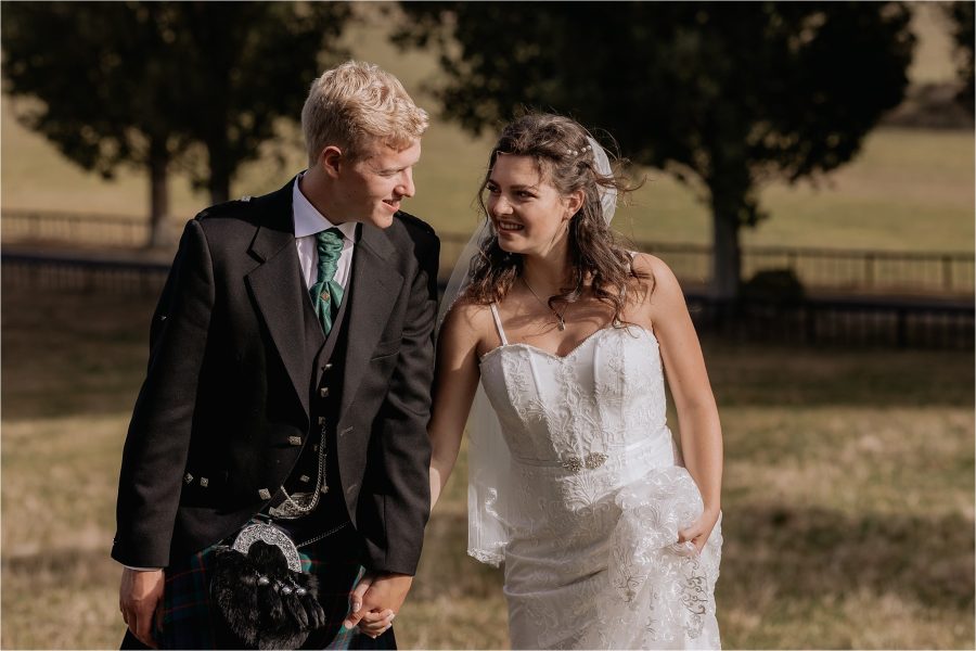 wedding photos couple walking holding hands in the country red barn New Zealand