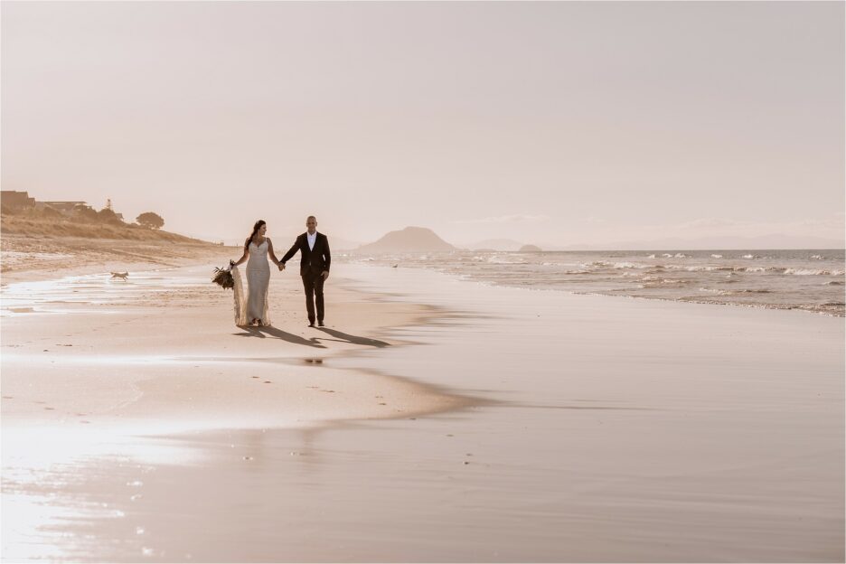 Bride and groom on beach with mount manganui behind them