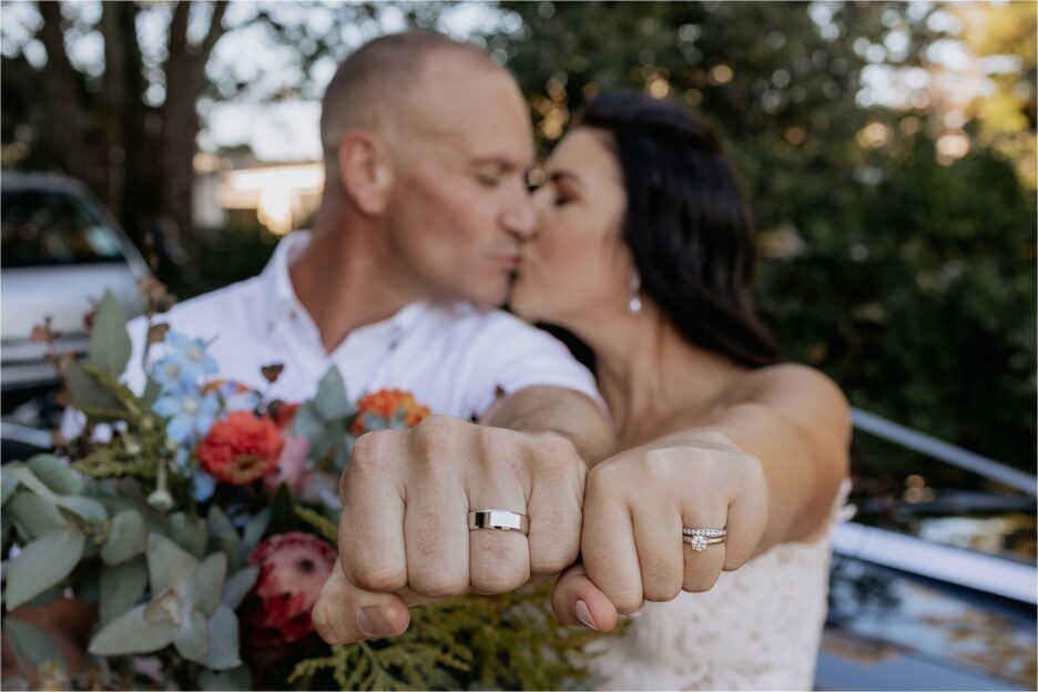 couple kiss with rings in foreground
