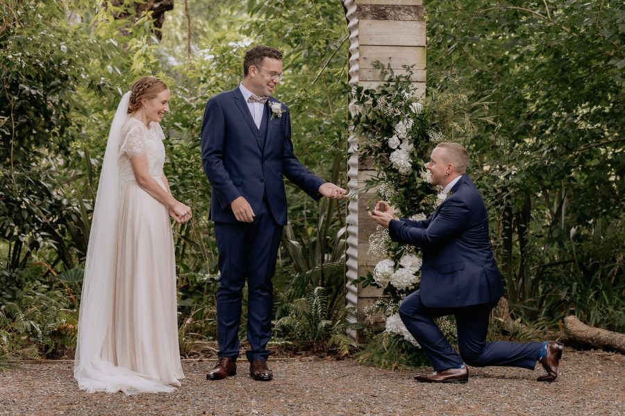 Best man hands Groom the rings kneeling