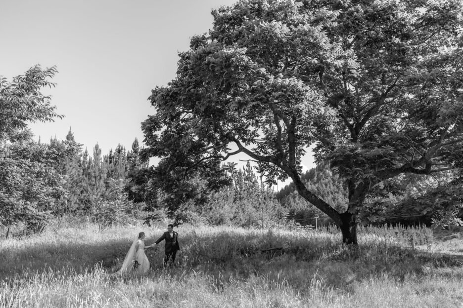 Groom and bride walking under Oak tree at Old Forest School