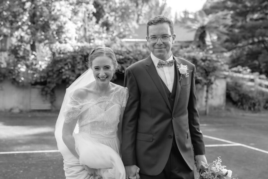 Happy relaxed wedding couple walking on tennis courts Old Forest School