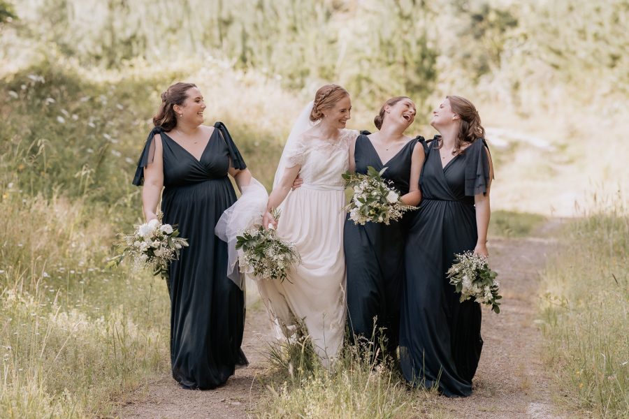 Bride walking with her sisters laughing at Old Forest school on country lane