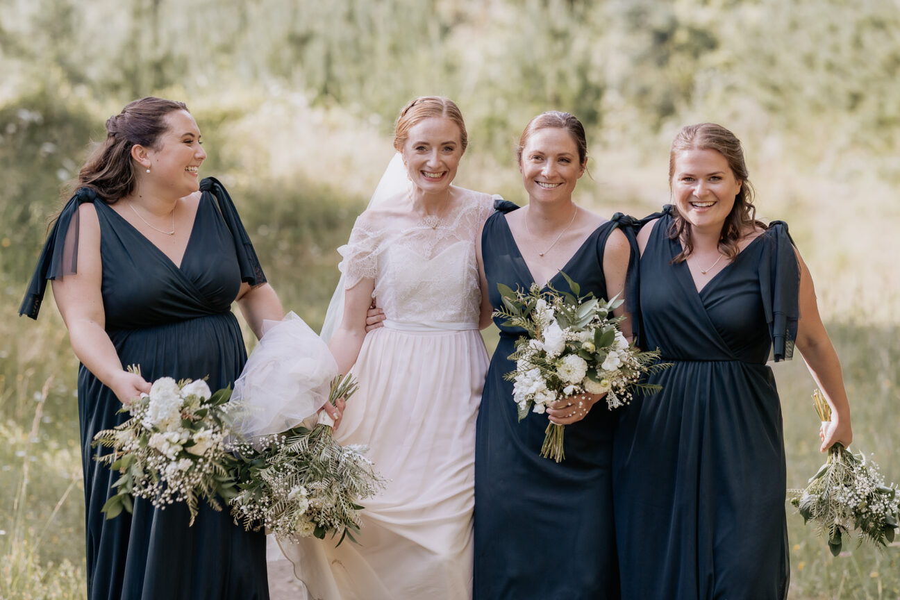 Relaxed happy bride with her green bridesmaids at Old Forest School