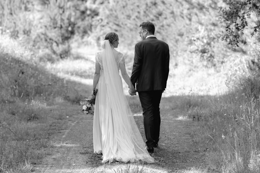 Wedding couple walking country lane in forest New Zealand