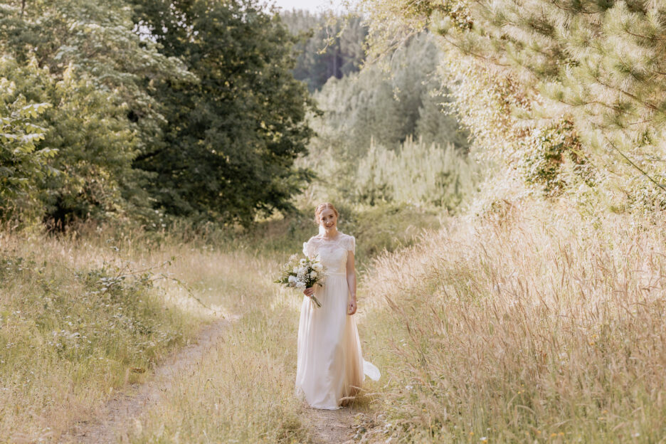 Bride walks country lane in golden high grass Old Forest School