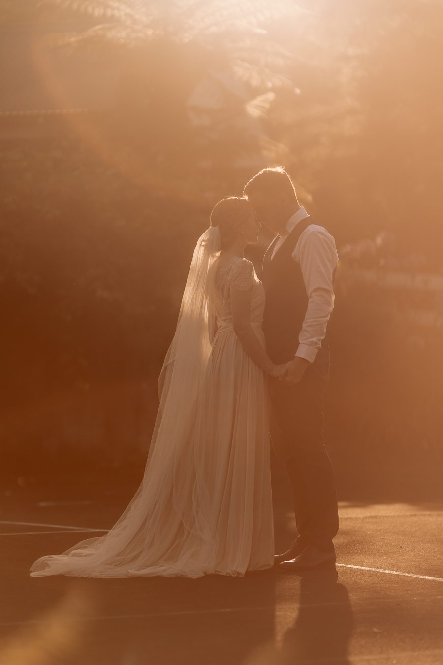 Old forest school wedding photo standing on tennis court with sunrays