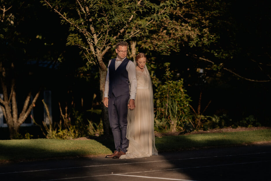 wedding couple bathed in late light on tennis courts at Old Forest School