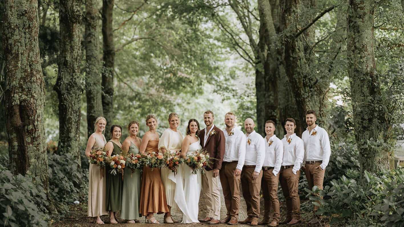 Country wedding party photo in rustic colours in beautiful driveway of The Run Whakatane