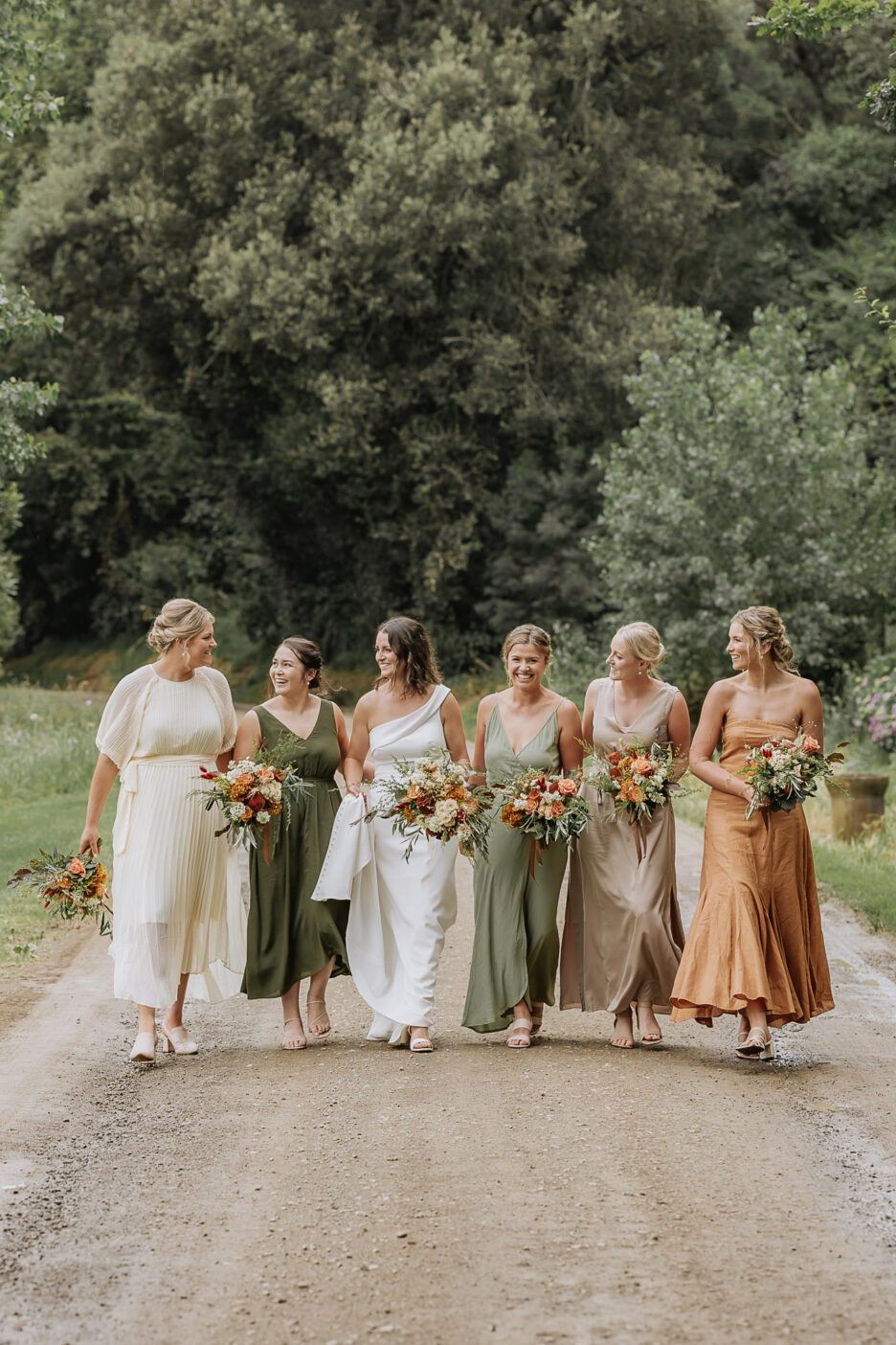 Bridesmaids walking with bride in rustic coloured dresses