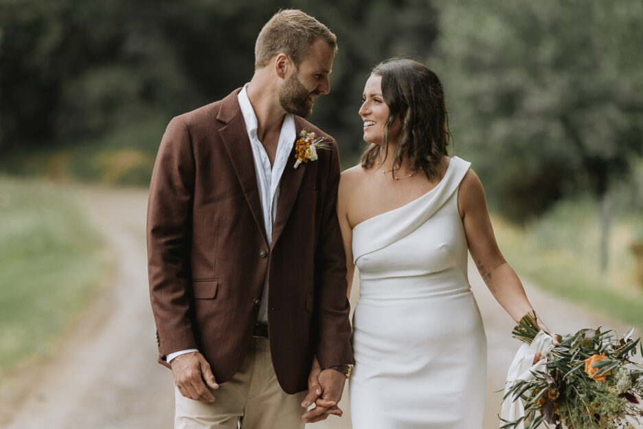 Bride and groom looking at each other walking in the country during photography at Whakatane