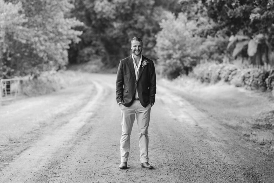 Groom standing on country road black and white