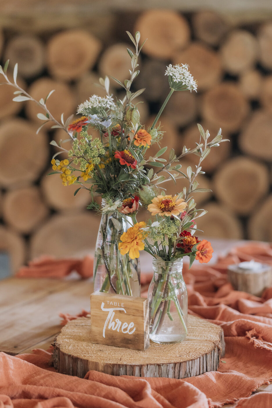 Wedding reception table flowers in glass jars with rustic fabric and country colours