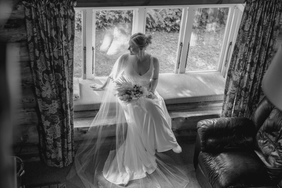 Bride sits in window seat of country cottage