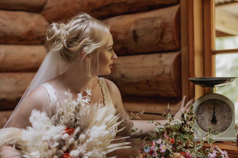 Bride looks out window before ceremony in country cottage