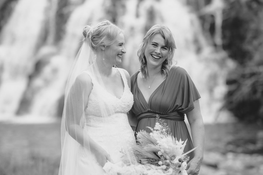 Bride and bridesmaids smiling during photos at Owharoa Falls Waihi