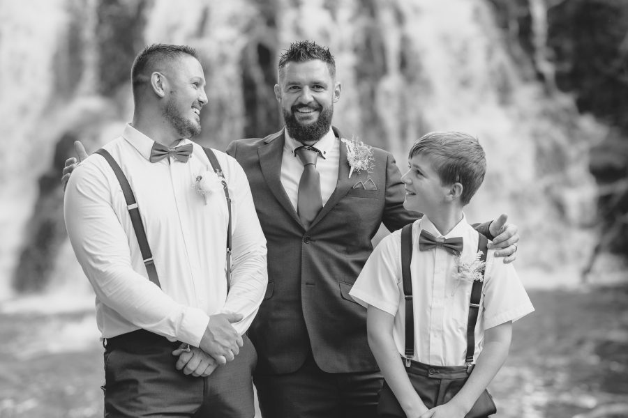 Groom with his groomsmen and son at waterfall at Falls Retreat Karangahake Gorge