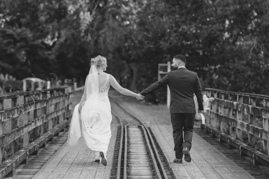 Wedding couple walking holding hands on historic bridge at Victoria battery Waihi