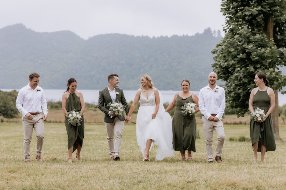 Wedding party in brown tones and olive green bridesmaids walking on field at Longfords Estate