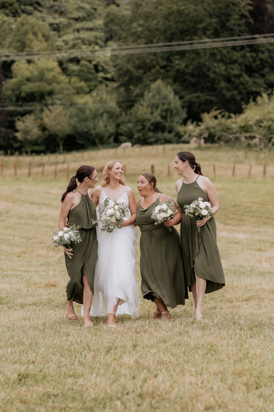 Bridesmaid pulling funny faces with bride walking at Longfords estate