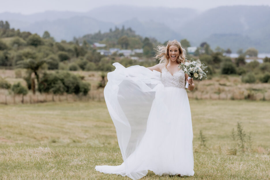 Bride having fun laughing in front of hills and Lake Okareka