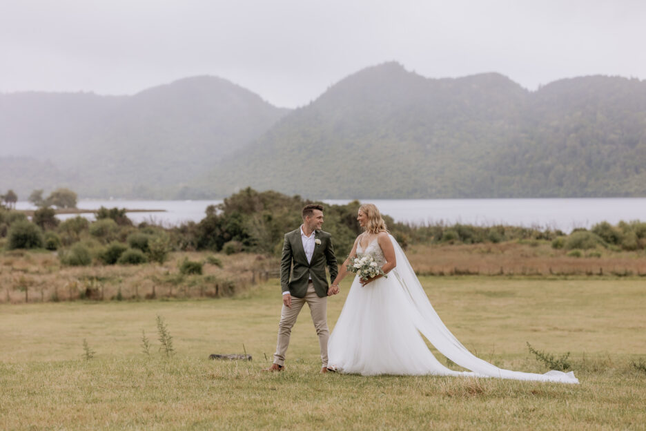 Bride and groom walking over field at lake Okareka Rotorua NZ