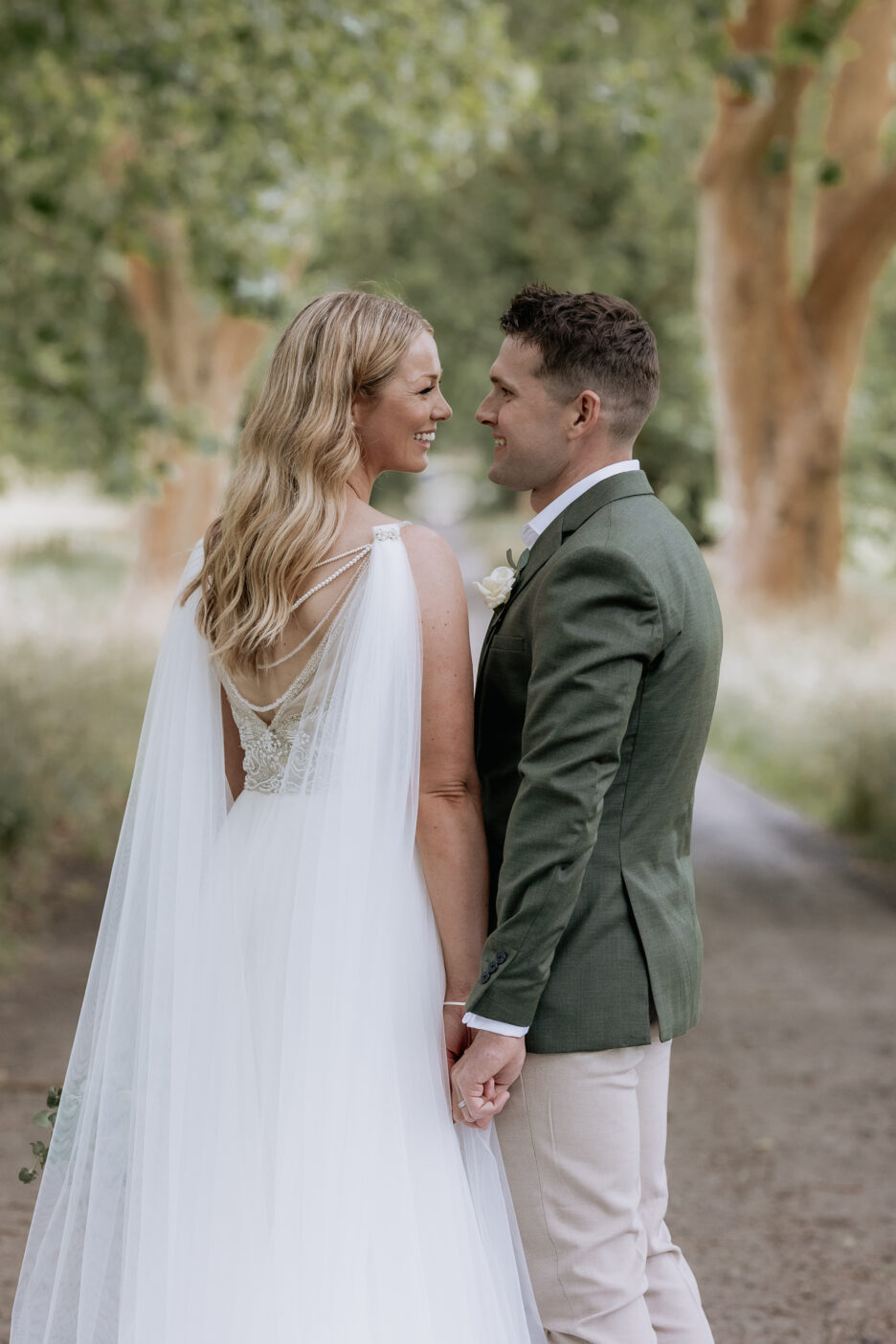 Wedding couple during photography on Longfords Estate country driveway looking at each other