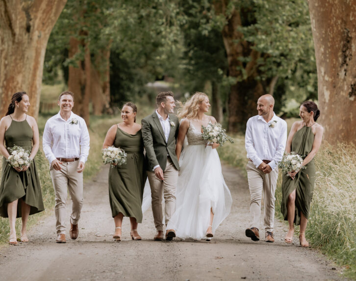 Olive green wedding party walking laughing driveway Longfords estate