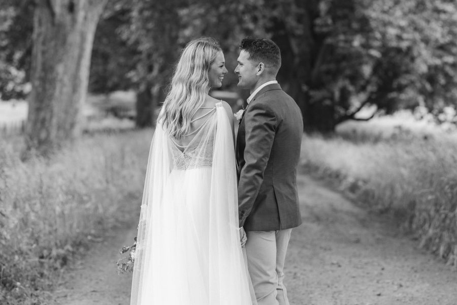 Couple in love looking at each other on wedding day back of Madison Rose gown visible