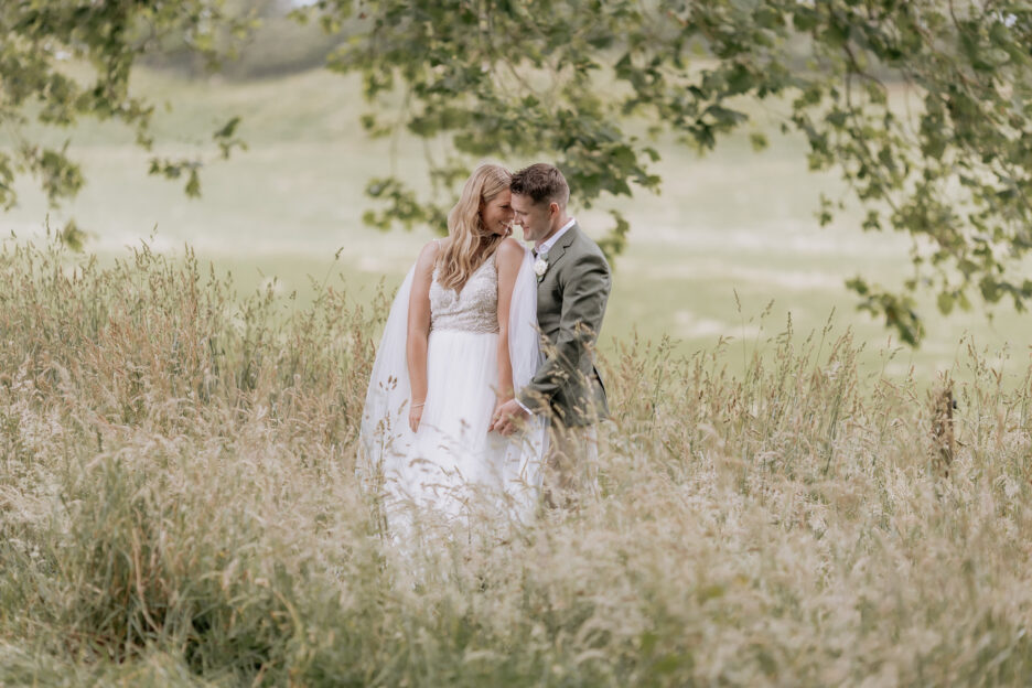 Wedding couple snuggling in field of high grass at Longfords estate