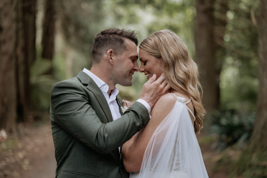 Groom in grass green jacket holds his brides face tenderly in a happy embrace