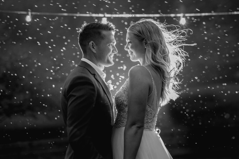 Happy bride and groom standing in the rain while the rain is lit up