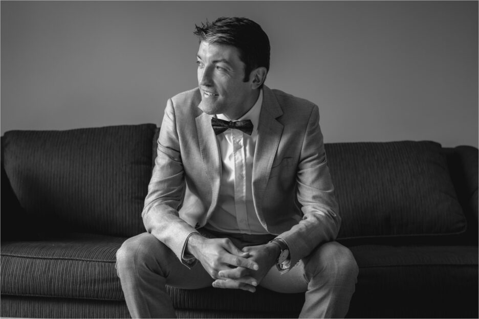 Black and white photo of groom sitting on couch