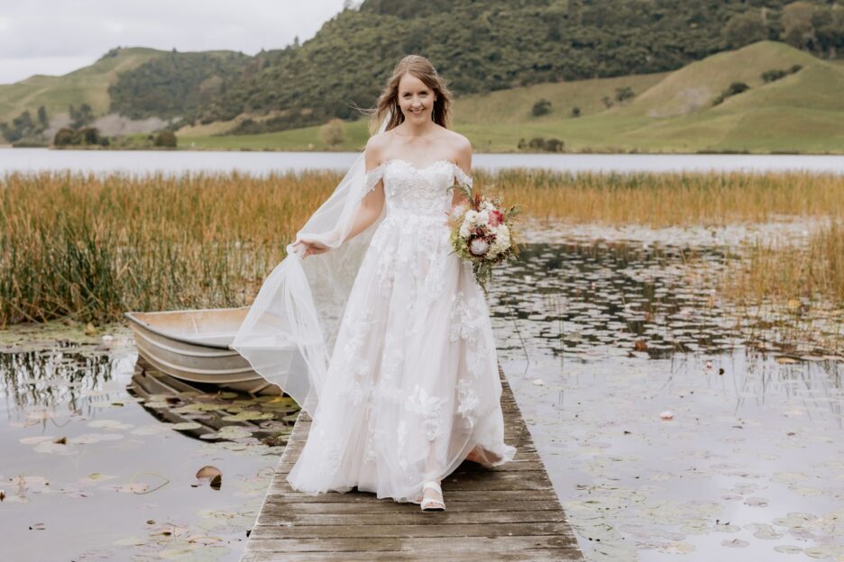 Bride walking in her madison rose wedding dress on wharf by lake