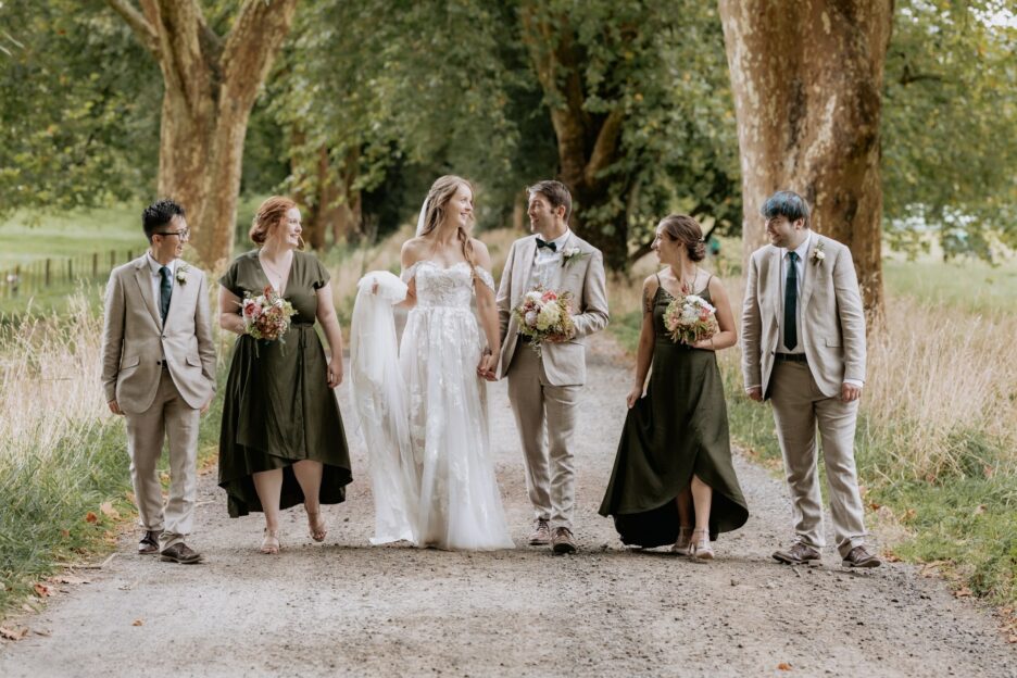 Wedding party walking on driveway girls in Olive green boys in linen suits