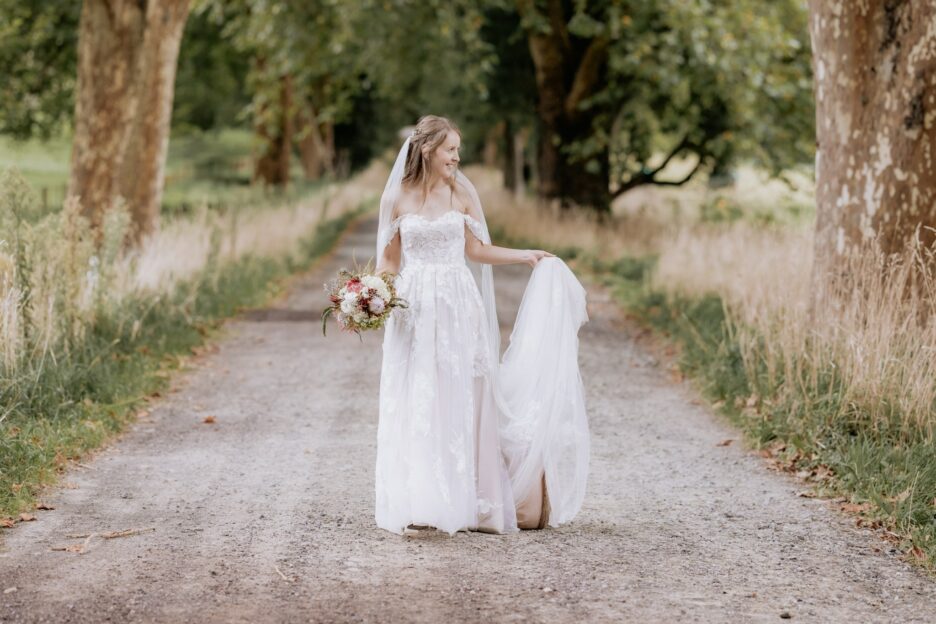 Bride walking on country lane holding her dress